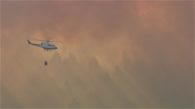 Un helicóptero intenta sufocar as lapas dun incendio