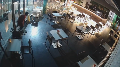 O ladrón entrando na cafetería tras romper a cristaleira