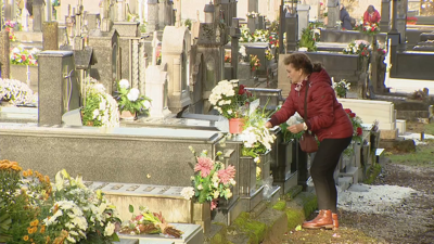 Unha muller arranxa a tumba familiar no cemiterio de Boisaca, Santiago, este sábado a primeira hora