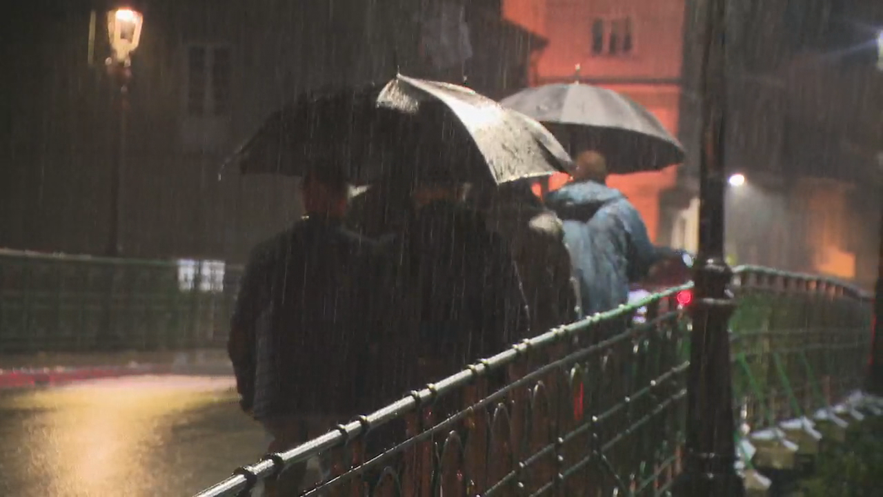 Persoas cubríndose da choiva en Ourense