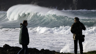Varias persoas pasean ante a forte ondada formada este luns na costa de Valdoviño, nas proximidades de la Iglesia do Porto. (EFE/Kiko Delgado), e Imaxe en directo da Cámara web da CSAG situada no Parador de Muxía