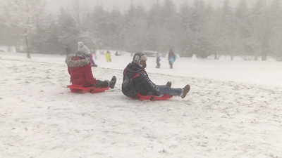 Dous visitantes dispóñense a escorregar pola neve