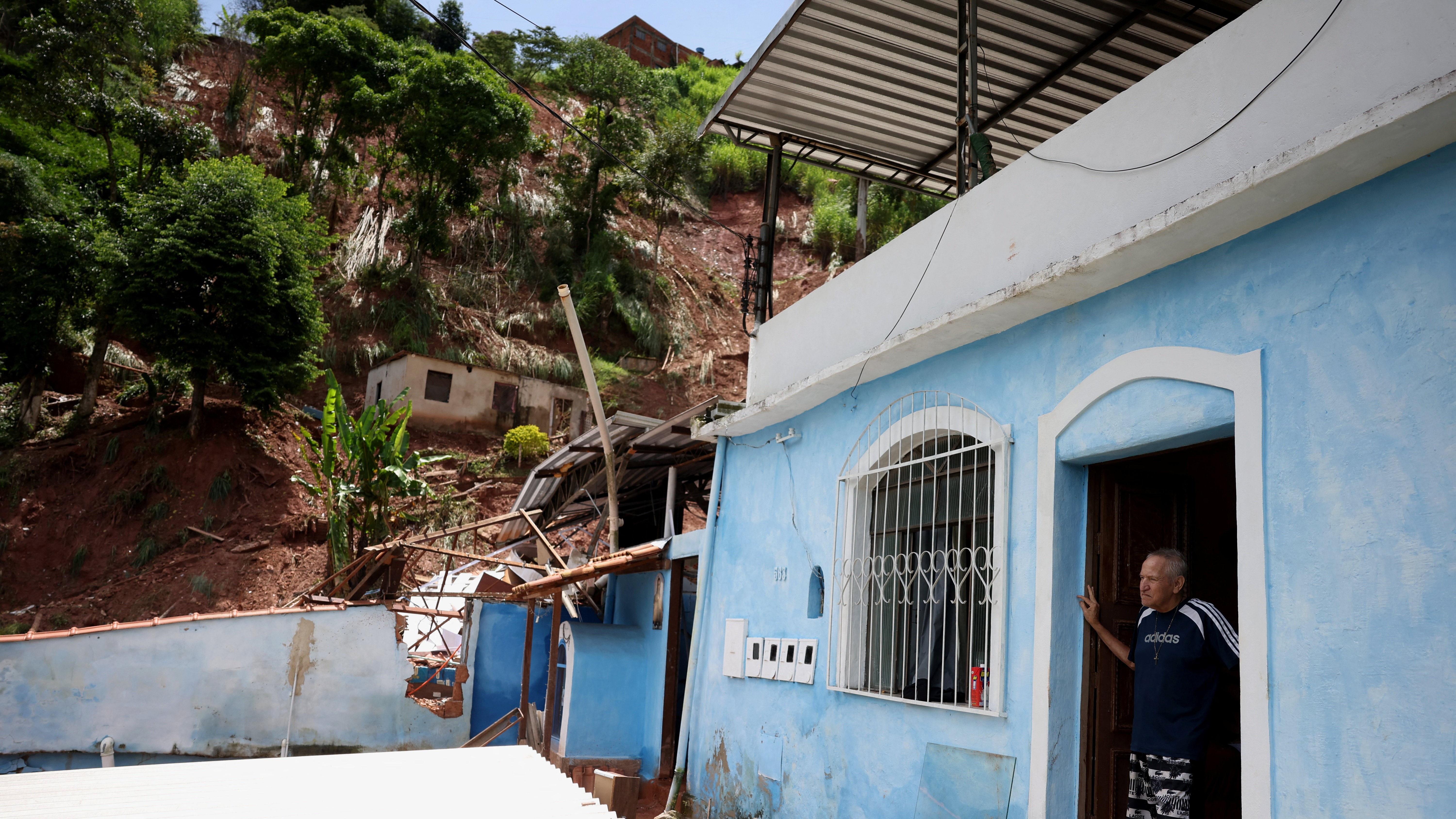 Un home encóntrase na entrada da súa casa xunto aos cascallos despois dunha caída de terra, en Juiz de Fora, estado de Minas Gerais, O Brasil, o 25 de febreiro de 2026. REUTERS/Pilar Olivares