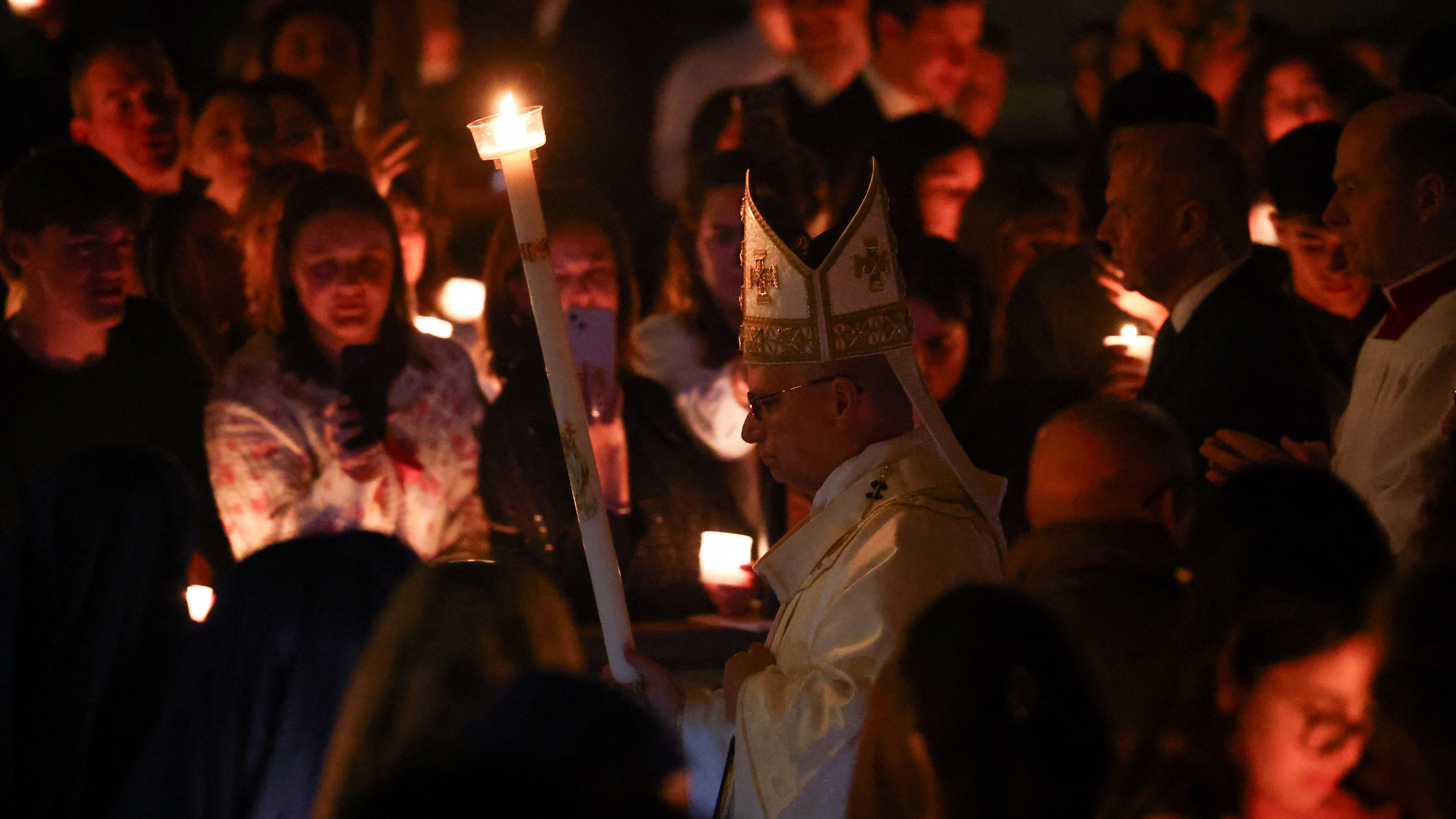 León XIV sostén unha candea mentres chega para liderar a Vixilia Pascual na Basílica de San Pedro. REUTERS/Guglielmo Mangiapane