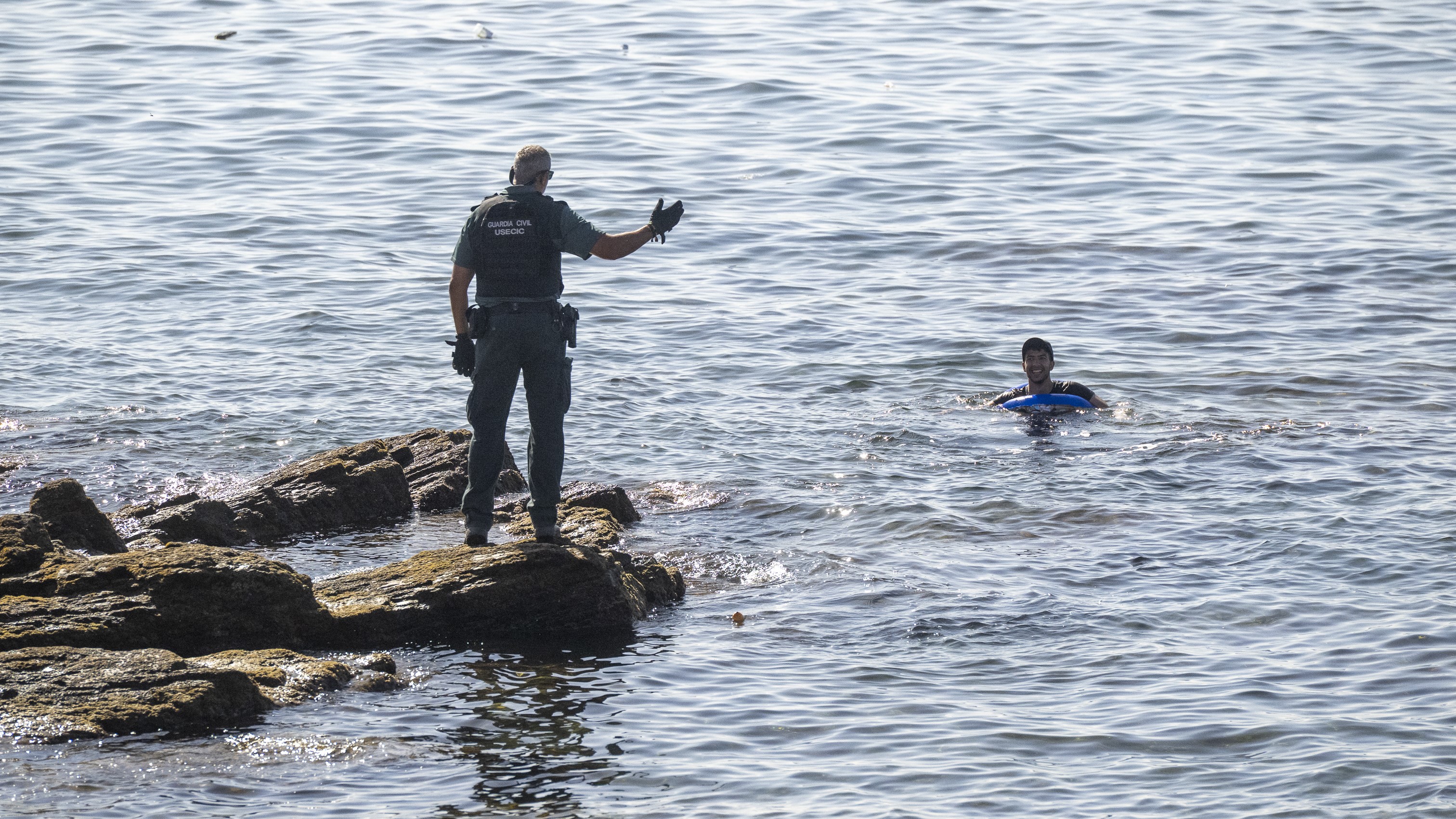 Un axente asiste unha persoa que nada no mar, en Ceuta, o pasado 2 de agosto (Marcos Moreno/Europa Press)