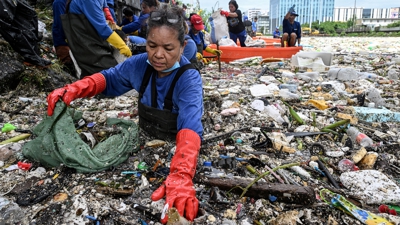 Muller que traballa no Departamento de Medio Ambiente e Recursos Naturais  recolle lixo que se lavou nun río no medio de fortes choivas monzónicas do suroeste preto da Igrexa Baclaran na cidade de Paranaque, Metro Manila, Filipinas. REUTERS